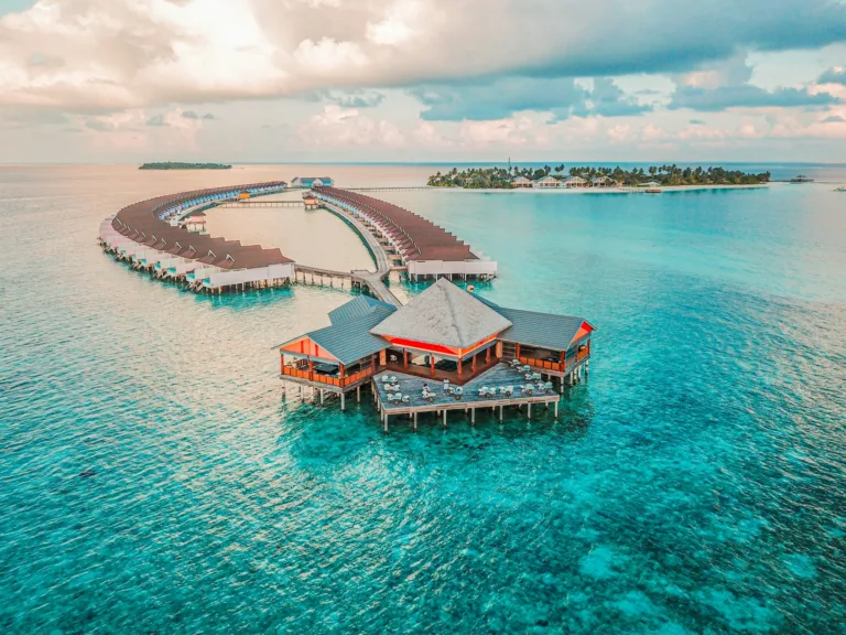 Vue aérienne d’un resort aux Maldives avec lagon turquoise, île tropicale et villas sur pilotis