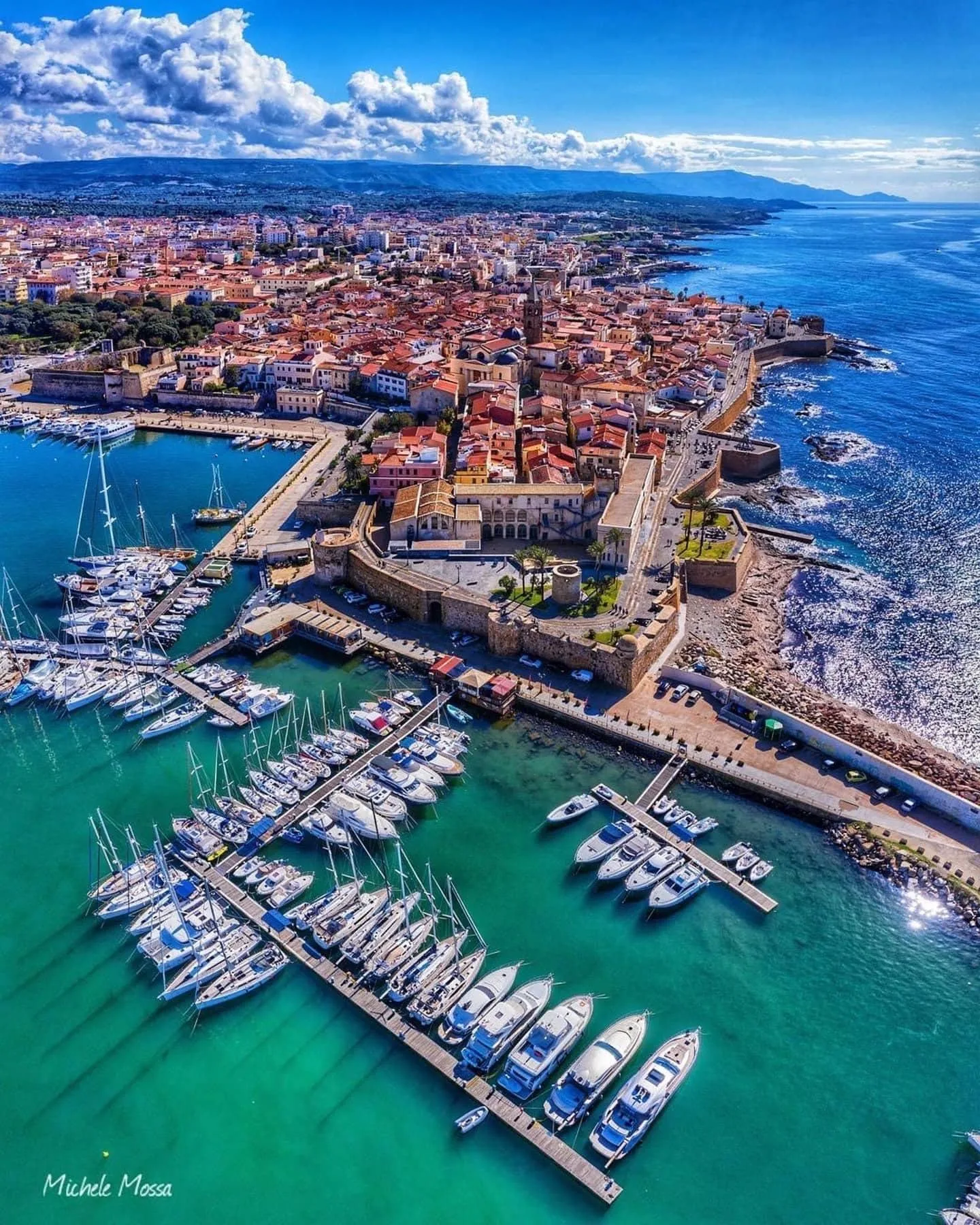 Aerial view of Alghero in Sardinia with old town, sea walls, marina and turquoise sea