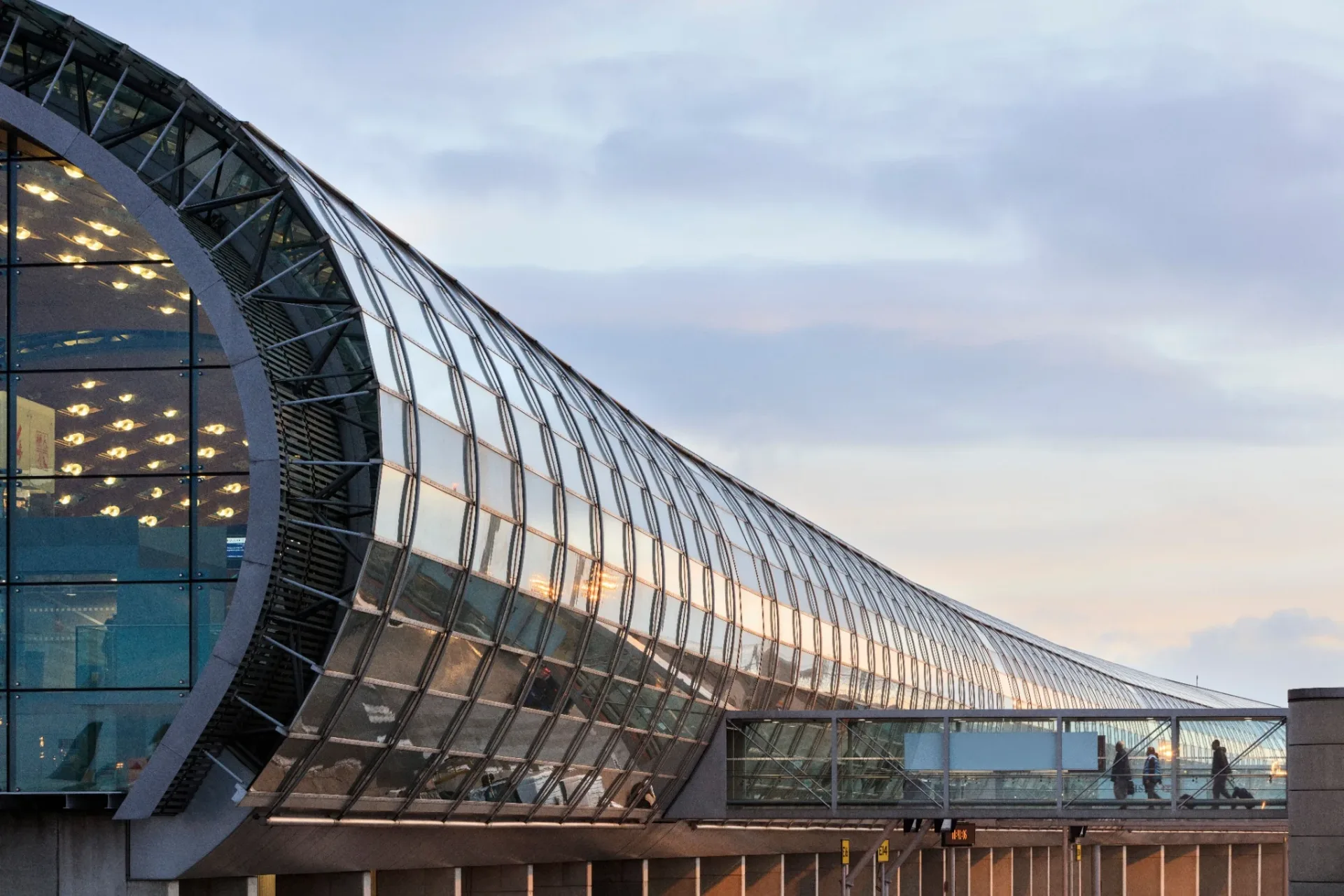 Passerelle vitrée et voyageurs dans l’aéroport Paris-Charles-de-Gaulle.