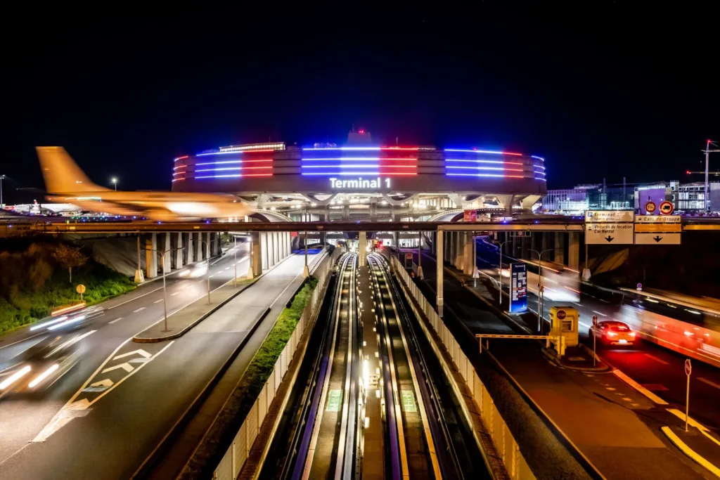 Terminal 1 de Paris-Charles-de-Gaulle illuminé la nuit en bleu, blanc et rouge.